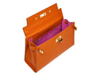 Inside of a large orange, natural grainy print Italian calf leather handbag with top handle, detachable strap and gold plated hardware showing the bright pink suede lined interior.