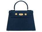 A large navy Italian leather, natural print handbag with gold hardware, a top handle with a detachable strap on a white background.