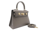 A taupe colored, medium-sized handbag made from grainy print Italian calf leather, featuring gold-plated hardware and a top handle with a detachable shoulder strap.