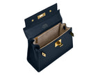 Inside of a navy blue Italian leather handbag with gold hardware, a top handle and a detachable strap showing the grey suede interior on a white background