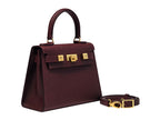 A burgundy wine coloured, medium-sized Italian leather handbag with a pebble print and gold plated hardware, featuring a top handle and a detachable shoulder strap.