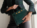 Woman holding a large dark green ‘croc’ print Italian calf leather handbag with top handle, detachable strap and gold plated hardware