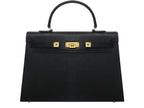 A black Maya Grande Dolomite handbag with gold plated hardware and a pebble print texture, featuring a top handle, detachable strap and gold accents.