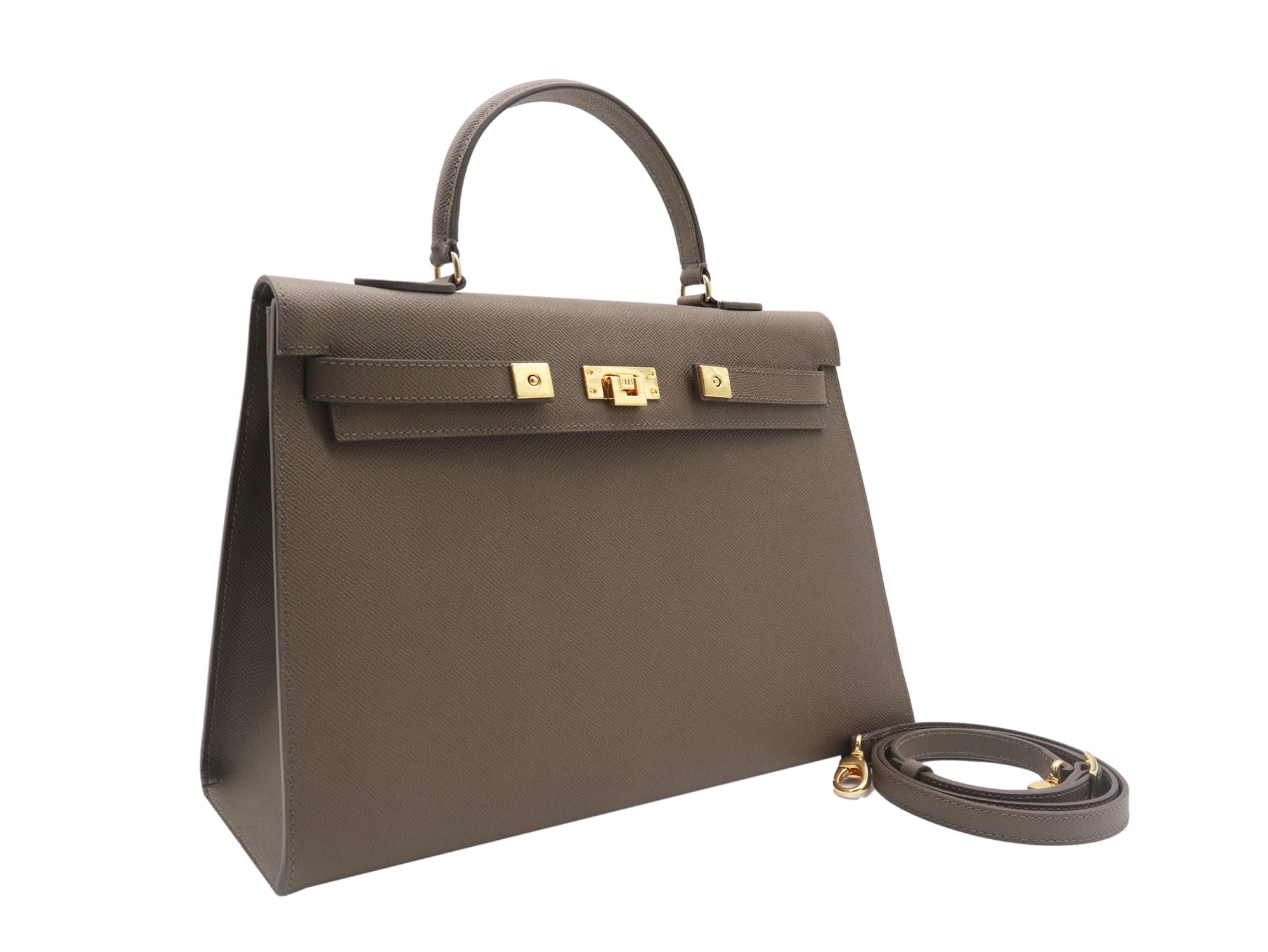 A large taupe colored Italian calf leather handbag with pebble print texture, gold plated hardware, and a top handle with a detachable strap.