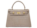 A stone-colored, croc print Italian calf leather handbag with a top handle, detachable strap, and gold plated hardware.