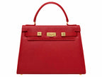 A red Italian natural print leather handbag with a top handle and a detachable shoulder strap, featuring gold-plated hardware and magnetic locks.
