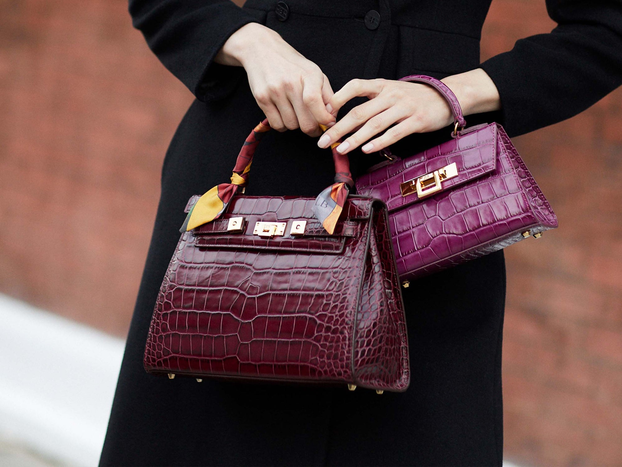 Woman carrying A large wine ‘croc’ print Italian calf leather handbag with top handle, detachable strap and gold plated hardware with magnetic fastening and a mignon dark pink handbag