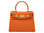 An orange luxury handbag with a top handle and gold-plated hardware, made of Italian calf leather.