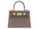 A taupe colored, medium-sized handbag made from grainy print Italian calf leather, featuring gold-plated hardware and a top handle with a detachable shoulder strap.