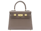 A taupe colored, medium-sized handbag made from grainy print Italian calf leather, featuring gold-plated hardware and a top handle with a detachable shoulder strap.