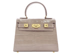 Stone coloured handbag with gold hardware on a white background