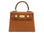 A tan-colored, pebble print Italian calf leather handbag with gold-plated hardware, a top handle and a detachable strap.