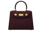 A burgundy wine coloured, medium-sized Italian leather handbag with a pebble print and gold plated hardware, featuring a top handle and a detachable shoulder strap.