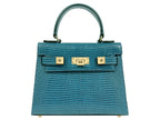 Blue textured ‘lizard’ print Italian leather handbag with gold hardware on a white background