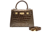 A bronze croc print Italian calf leather luxury handbag with gold plated hardware and a top handle.