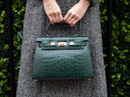 Woman carrying a large dark green ‘croc’ print Italian calf leather handbag with top handle, detachable strap and gold plated hardware