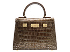 A bronze croc print Italian calf leather luxury handbag with gold plated hardware and a top handle.