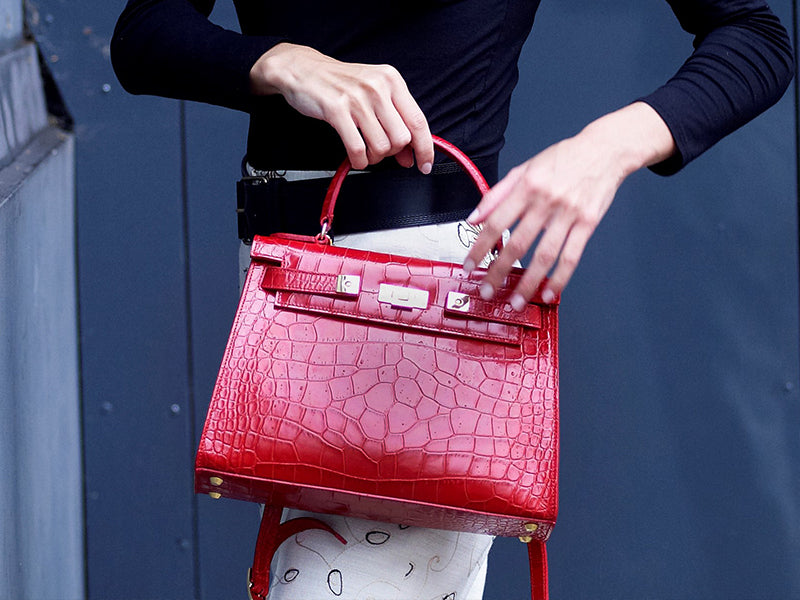 A large red, ‘croc’ print Italian calf leather handbag with top handle, detachable strap and gold plated hardware.